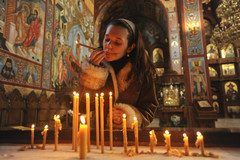 Olga Spivak of Lindenhurst kisses a candle before placing it with others she lit for the health and well-being of loved ones while at Protection of the Most Holy Mother of God, also called the New Gracanica Monastery, in Third Lake. | Ryan Pagelow~Sun-