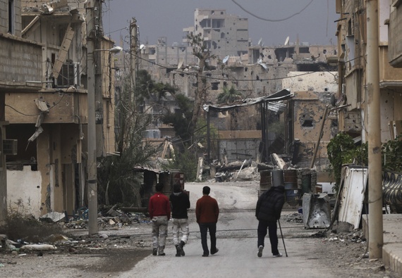 Free Syrian Army fighters walk along a street in Deir al-Zor that has been scarred by war. Photo: Khalil Ashawi/Reuters