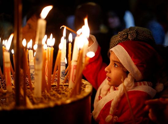 Палестинская девочка зажигает свечу в храме Рождества Христова в Вифлееме. 06/01/2014. 