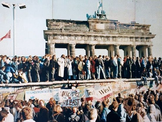 Берлинская стена с взобравшимися на неё немцами на фоне Бранденбургских ворот