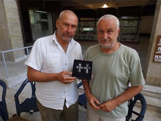 Archaeologists Nikolay Ovcharov (left) and Angel Konakliev (right) with the 14th century lead cross reliquary found in the medieval city of Missionis / Krum’s Fortress near Bulgaria’s Targovishte. Photo: 24 Chasa daily