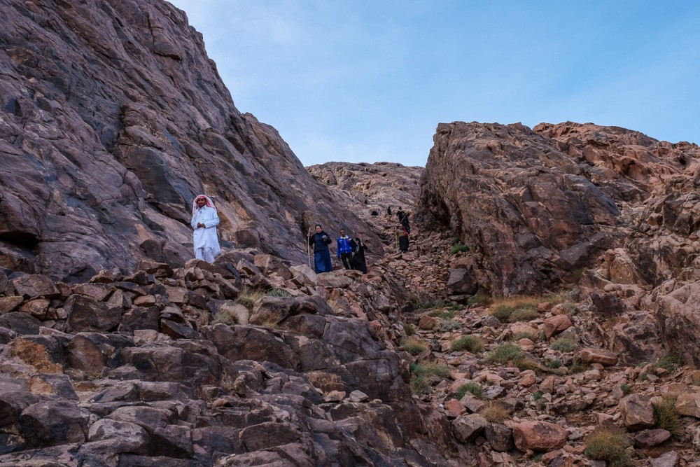 Паломники, ведомые бедуином, спускаются с горы