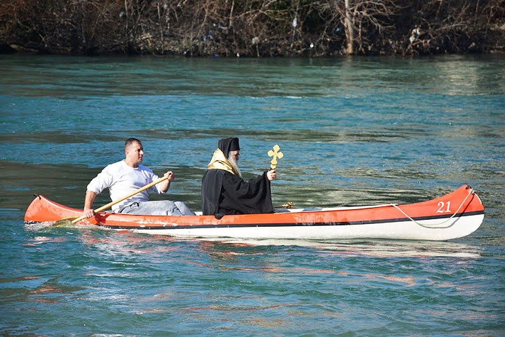 Metropolitan Amfilohije canoes out with the cross to the middle of the river.