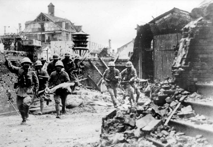 Japanese officer and soldiers walk the streets of the devastated Chinese city.