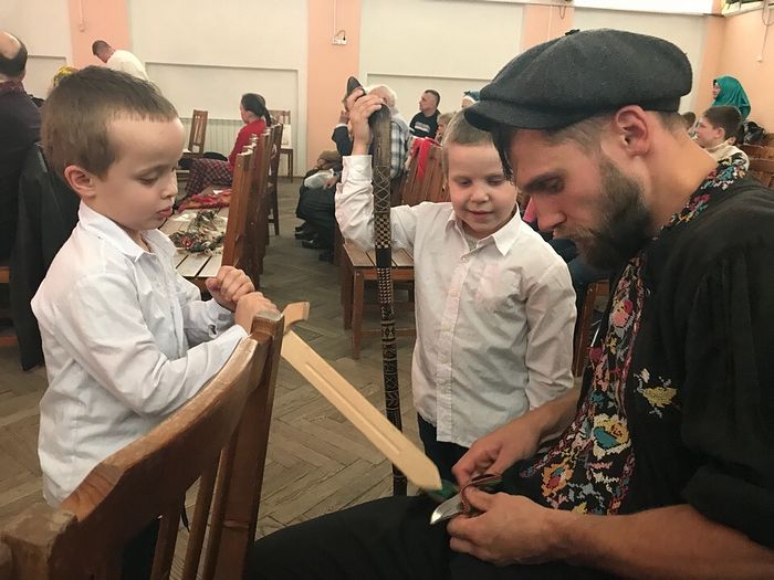 Денис Антипов в Луге на фестивале объясняет детям значение символов на тростке