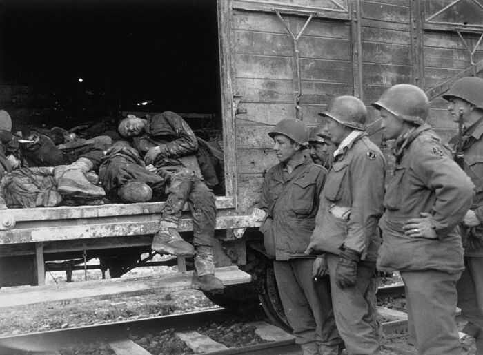 Soldiers of the U.S. 42nd infantry division at a train car with the bodies of prisoners from Dachau
