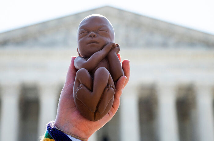 Демонстранты, выступающие за жизнь, держат макет не родившегося ребенка, ожидая законодательного решения об абортах перед Верховным судом США в Вашингтоне, округ Колумбия, 22 июня 2020 года. | Jim Watson/AFP Getty Images