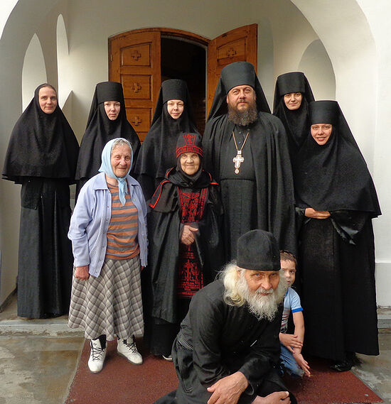 Elena before her tonsure, in a blue kerchief with the sisters of the Kazan-St. Tryphon Hermitage and the spiritual father of the monastery, Igumen Savvaty