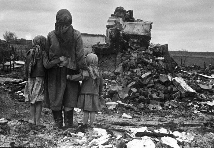 Русская мать и две ее дочери рассматривают разрушение своего дома после Второй Смоленской битвы. Осень 1943 года