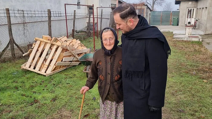 Fr. Ciprian Ioniță, head of the Romanian Patriarchate’s Philanthropic Department meets with an elderly woman who received Church assistance. Photo: basilica.ro