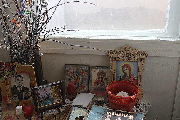 A table with icons and family photos at Liudmila Filippovna’s house.